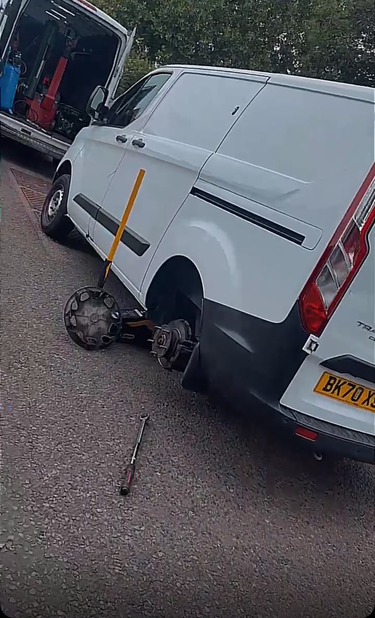White Ford Transit Custom van on the roadside with its rear wheel removed and our service van alongside